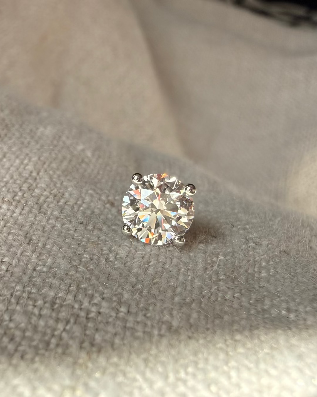 AUREN AND CO Single diamond earring on a textured beige surface