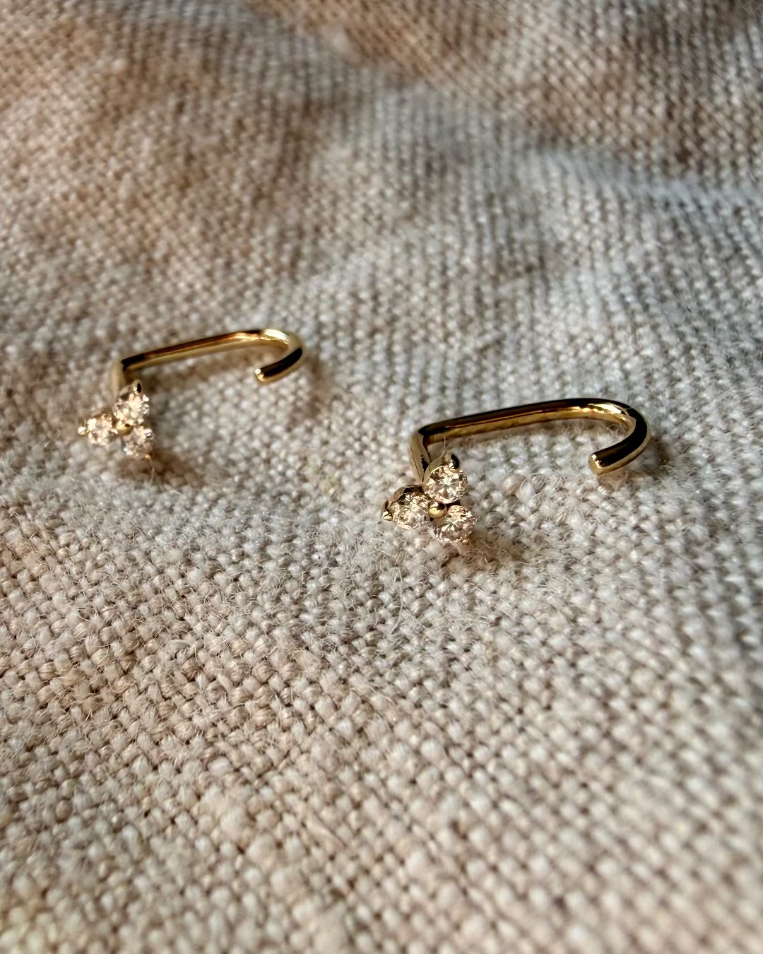 Gold nose ring with small diamonds on a textured beige surface